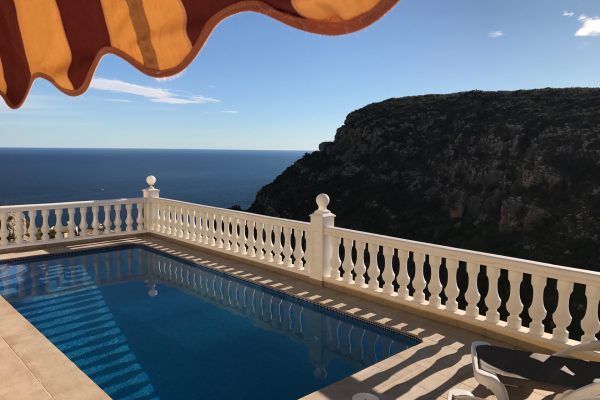 Looking across the sunny heated pool at Casa Windlenook, with views of the sea and mountains