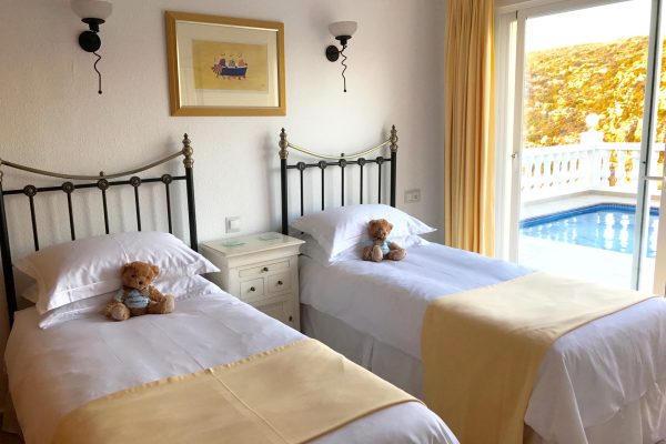 Twin beds with teddy bears and sliding glass doors accessing the pool terrrace